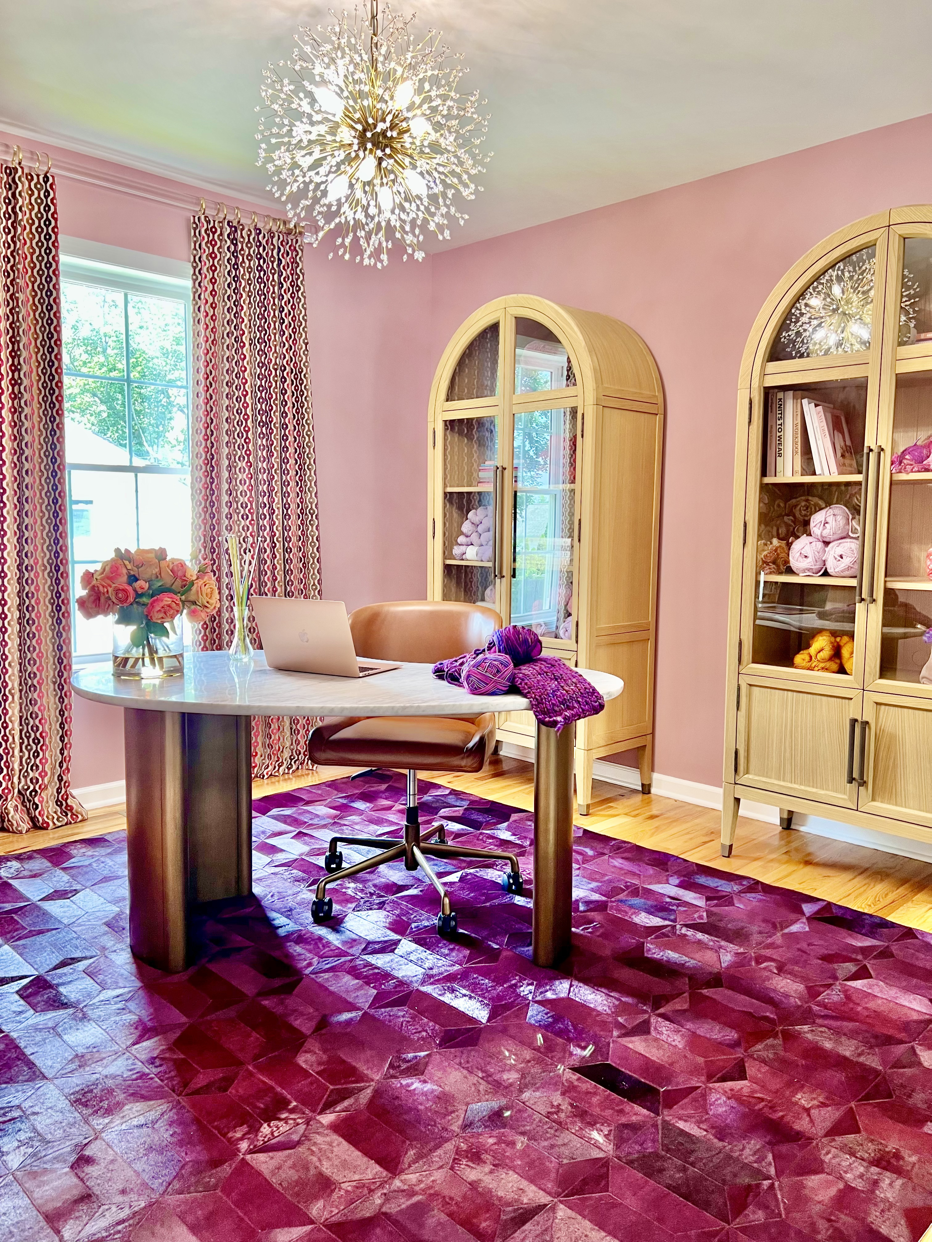 A pink home office with arched cabinets and a deep magenta rug