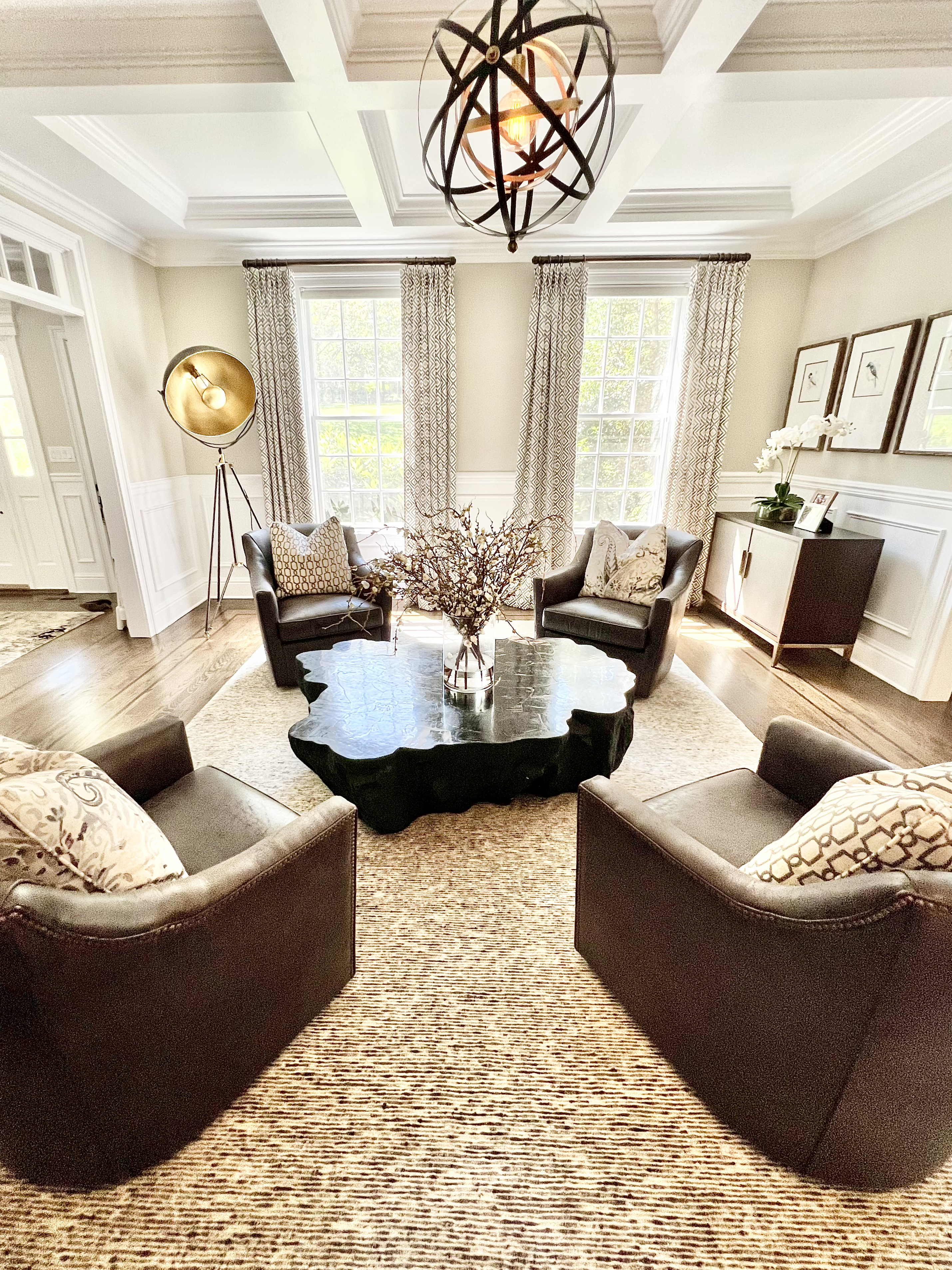 A formal living room with leather chairs, a coffered ceiling and a sculptural coffee table